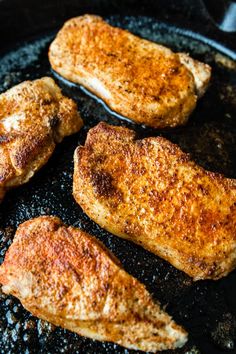 three pieces of chicken cooking in a frying pan