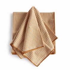 three brown and white checkered napkins sitting on top of each other, one folded up