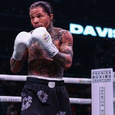 a tattooed man wearing boxing gloves standing in the ring