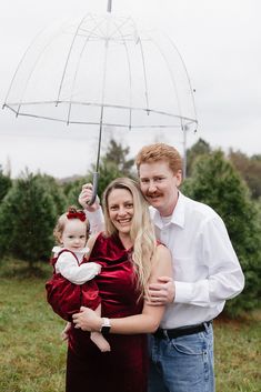 a man and woman holding a baby under an umbrella