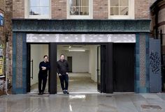 two men standing in the doorway of an empty building