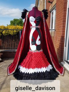 a woman's dress made out of red and black feathers with a cape on top