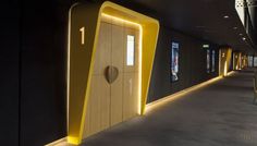 the entrance to an office building with yellow and black accents on the walls, along with two large wooden doors