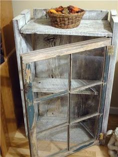 an old wooden cabinet with glass doors and a wicker basket sitting on top of it