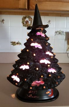 a black plastic christmas tree with pink and white clouds on it's top sitting on a kitchen counter