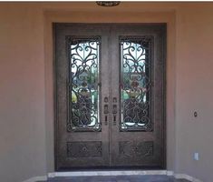 the front door to a home with wrought iron doors and glass panels on each side