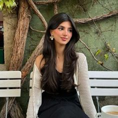 a woman sitting on a bench next to a cup of coffee