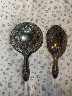 two spoons sitting next to each other on top of a floral covered table cloth