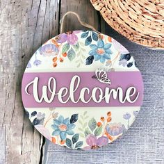 a welcome sign hanging from the side of a wooden wall next to a wicker basket