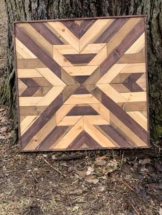 a wooden sign sitting next to a tree on the ground in front of a forest