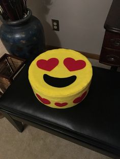 a smiley face cake sitting on top of a black table next to a blue vase