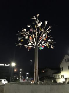 a metal tree with multicolored stars on it in the middle of a street