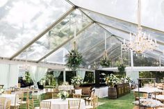 the inside of a tent with tables, chairs and chandeliers set up for an event