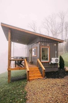 a small house with stairs leading up to the front door and covered patio area in foggy weather