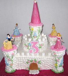 a birthday cake with princess figurines sitting on it's side and the number 3