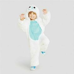 a little boy dressed in a white and blue monster costume with hands up to the side