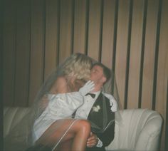 a bride and groom kissing on the couch