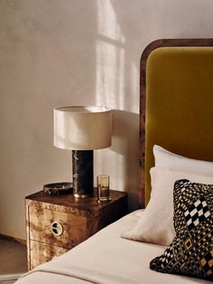 a bedroom with a bed, night stand and lamp on the bedside table next to it