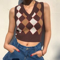 a woman standing in front of a white wall wearing a brown and white knitted sweater