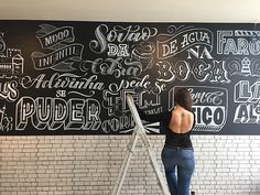 a woman standing on a ladder in front of a chalkboard with writing all over it