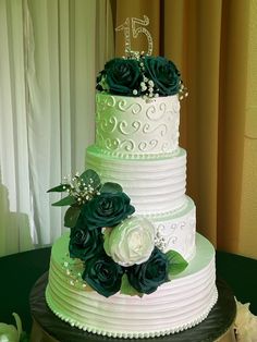 a three tiered wedding cake with green and white flowers