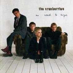 the cranberries sitting on a couch in front of a white wall with words