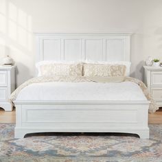 a white bed sitting on top of a wooden floor next to a dresser and mirror