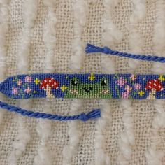 a blue beaded key chain with flowers and mushrooms on it, sitting on a white surface