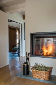 a fire place in the middle of a room with a basket and pen on it