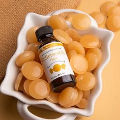 a white bowl filled with yellow candies next to a bottle of marmalade