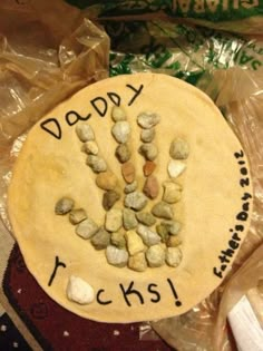 a cake decorated with rocks and the words daddy rocks written on it is surrounded by plastic bags