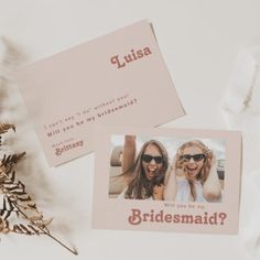 two bridesmaid cards on top of a white table next to some dried flowers