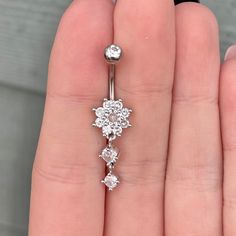 a close up of a person's hand holding a diamond navel ring