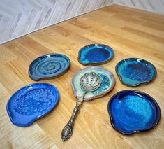 six blue dishes with spoons on a wooden table next to a wood floor in the background