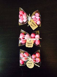 three bags filled with pink and white candies sitting on top of a wooden table