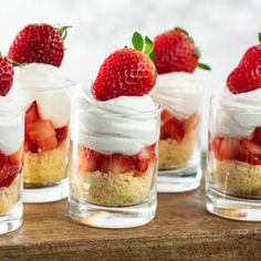 strawberry shortcakes with whipped cream and fresh strawberries in small glass jars on a wooden table