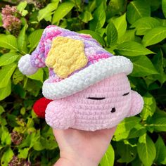 a hand holding a small crocheted toy with a hat on it's head