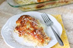 a white plate topped with lasagna covered in sauce and cheese next to a glass casserole dish