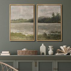 two paintings on the wall next to a chair and bookshelf in a room