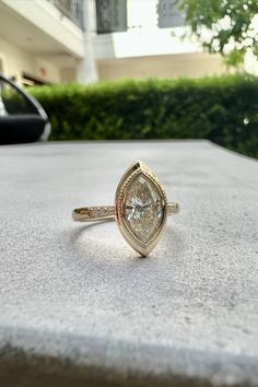 a diamond ring sitting on top of a stone table next to a building and bushes