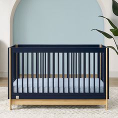 a baby crib in front of a green wall with a plant next to it