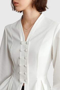 Elevate your wardrobe with this elegant white Cambered Shirt with Buttons. Its cambered V neckline and long sleeves make a sophisticated statement. Crafted from a soft fabric, it promises comfortable all-day wear. Add a touch of sophistication to any look with this stylish piece. Fabric: Cotton, Polyester Formal Tops Design, Elegant Tops And Blouses, Women Shirt Designs, Formal Blouses, Button Fashion, Fancy Shirt, Statement Blouse, Formal Tops, Blouse Casual Fashion