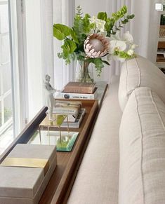 a living room filled with furniture and flowers on top of a table next to a window