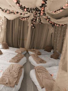 two beds are covered with white sheets and pink flowers on the headboard, along with sheer curtains