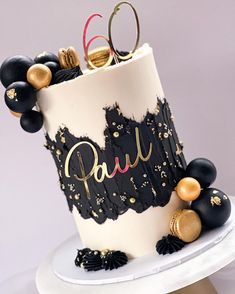 a black and white cake with gold decorations on it's top, sitting on a plate