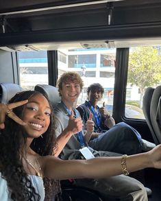 three people sitting in the back of a bus with their thumbs up and one person standing next to them