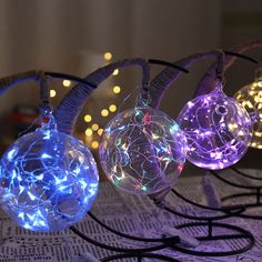 three ornaments with lights on them sitting on a table