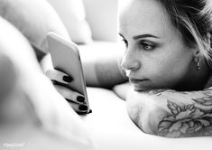 black and white photo of a woman with tattoos looking at her phone - stock photo - images