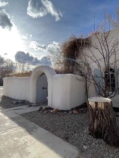 a white building with a tree in front of it and some rocks on the ground