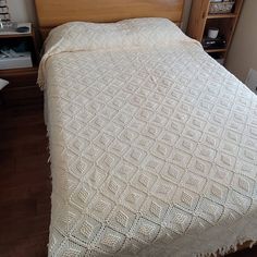 a bed with a white bedspread on top of it next to a book shelf